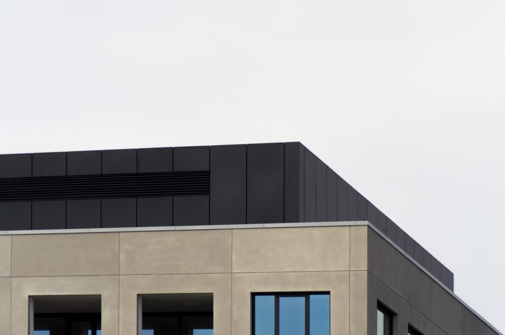 concrete building with mirror windows clear sky - Takspesialisten